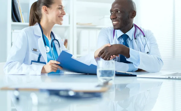 Two happy smiling young medical people handshaking at office