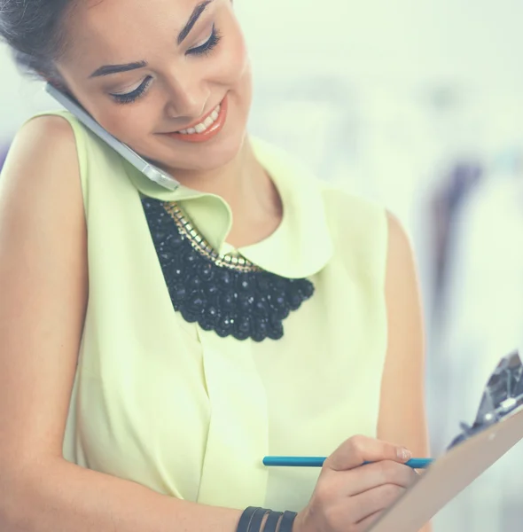 Pretty fashion designer working in office using mobile phone