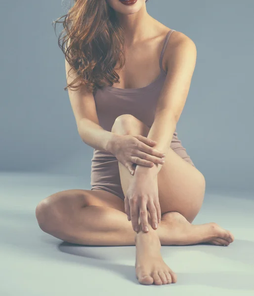 Beautiful barefoot woman sitting on the floor
