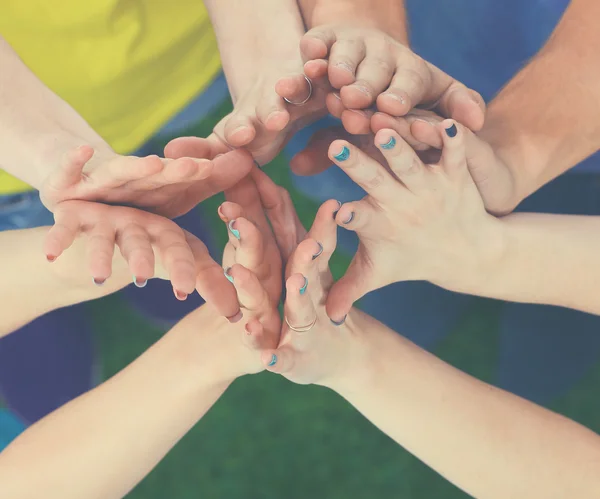 People joining their hands  on green grass