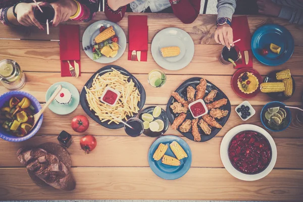 Top view of group of people having dinner together while sitting at wooden table