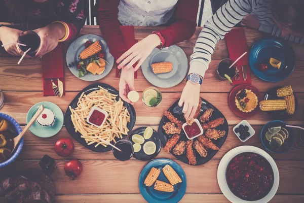 Top view of group of people having dinner together while sitting at wooden table