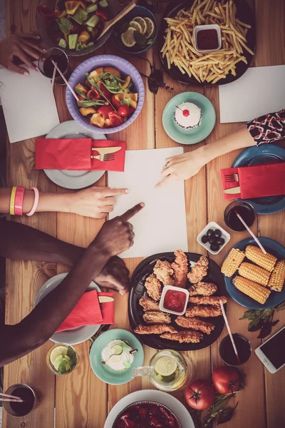 Top view of group of people having dinner together while sitting at wooden table