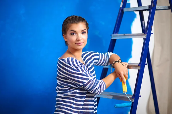 Happy beautiful young woman doing wall painting, standing on la