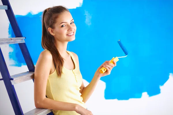 Happy beautiful young woman doing wall painting, sitting on lad