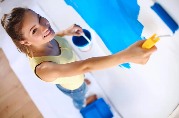 Happy beautiful young woman doing wall painting, standing on la