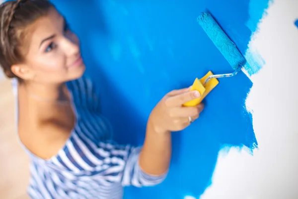 Happy beautiful young woman doing wall painting,