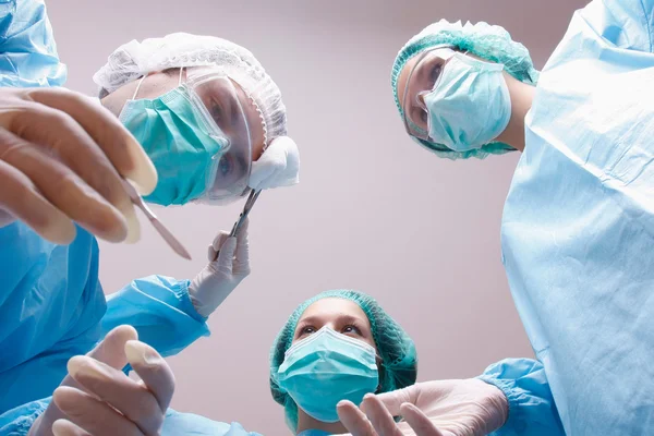 Below view of surgeons holding medical instruments in hands