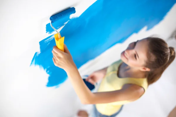 Happy beautiful young woman doing wall painting, standing