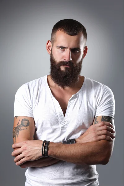 Portrait of handsome bearded man standing with crossed arms, isolated on grey background