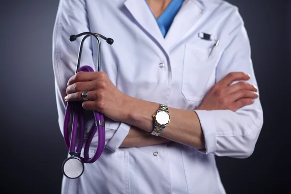 Portrait of young female doctor holding a stethoscope, isolated on black background