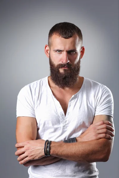 Portrait of handsome bearded man standing with crossed arms, isolated on grey background