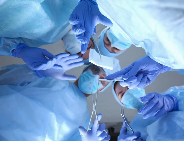 Surgeons holding medical instruments in hands and looking at patient