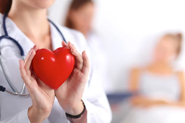 Young woman doctor holding a red heart, isolated on white background