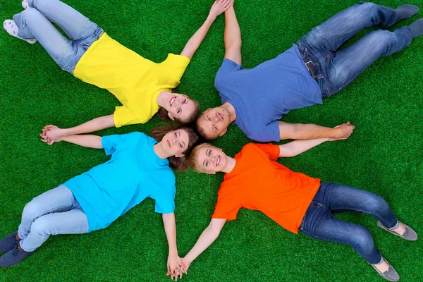 Group of young  people lying on green grass