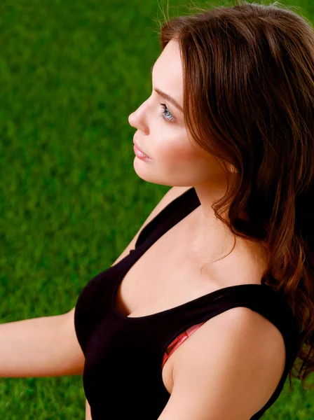 Woman sitting with crossed legs on the green grass