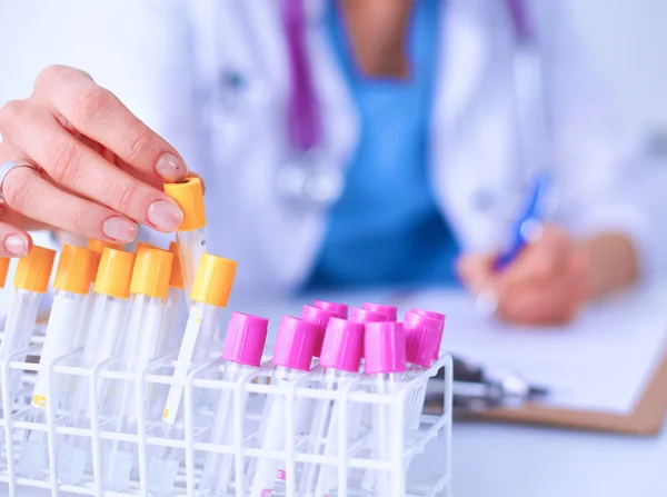 Woman researcher is surrounded by medical vials and flasks