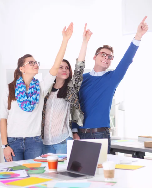 Young business people standing at office near desk and pointing up