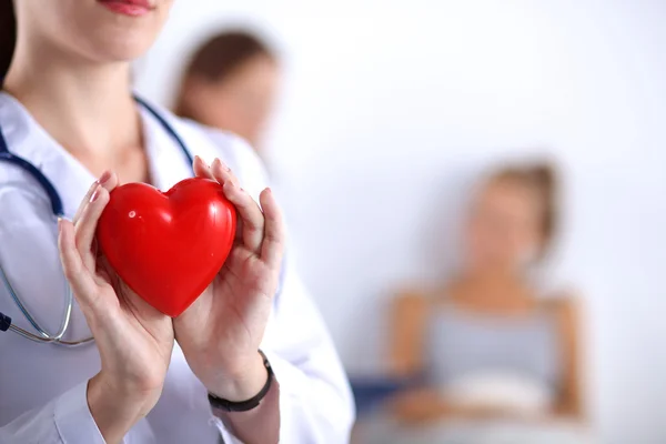 Young woman doctor holding a red heart, isolated on white background