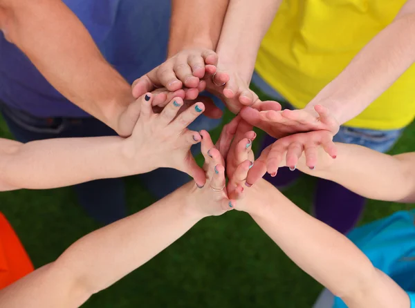 People joining their hands  on green grass