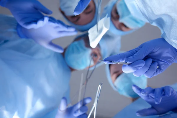 Surgeons holding medical instruments in hands and looking at patient