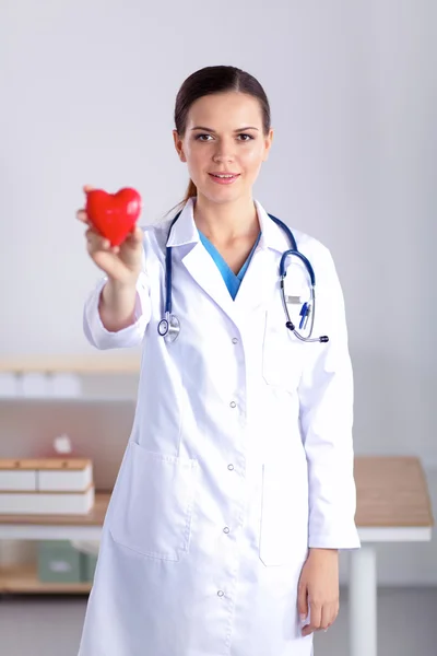 Young woman doctor holding a red heart, isolated on white background
