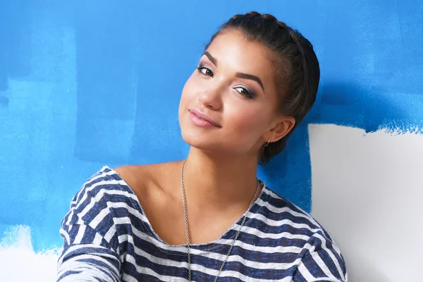 Happy beautiful young woman doing wall painting, standing near ladder