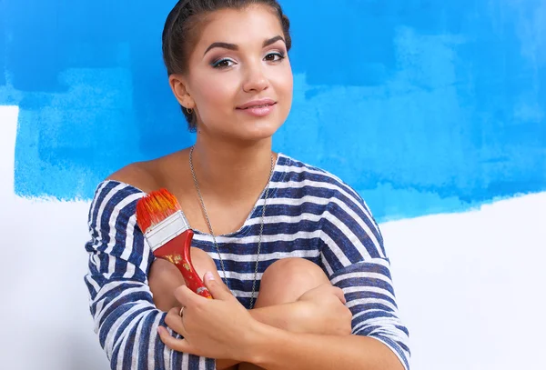 Portrait of female painter sitting on floor near wall after painting.