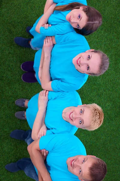 Group of young  people standing on green grass