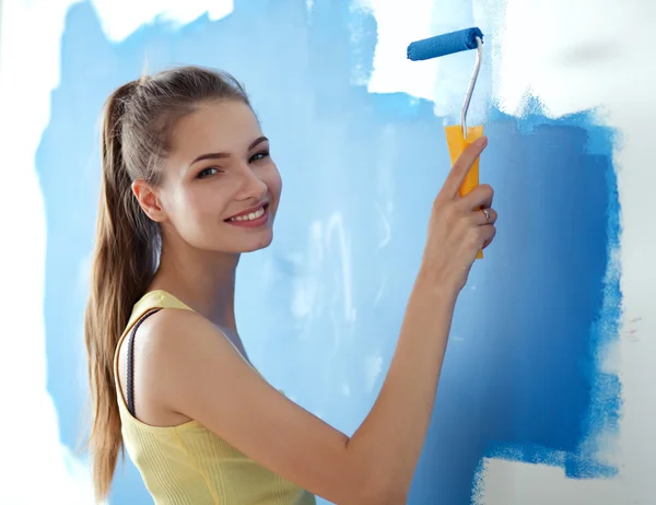 Beautiful young woman doing wall painting standing .