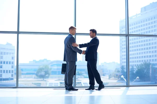 Full length image of two successful business men shaking hands with each other