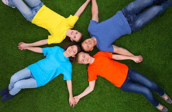 Group of young people lying on green grass