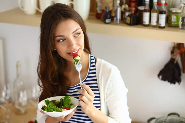 Young woman eating salad and holding a mixed salad