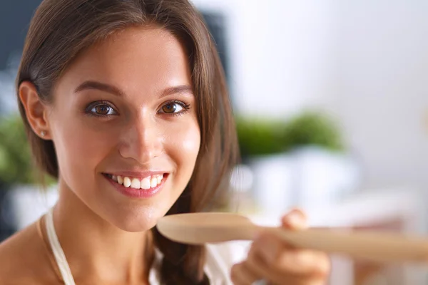 Cooking woman in kitchen with wooden spoon