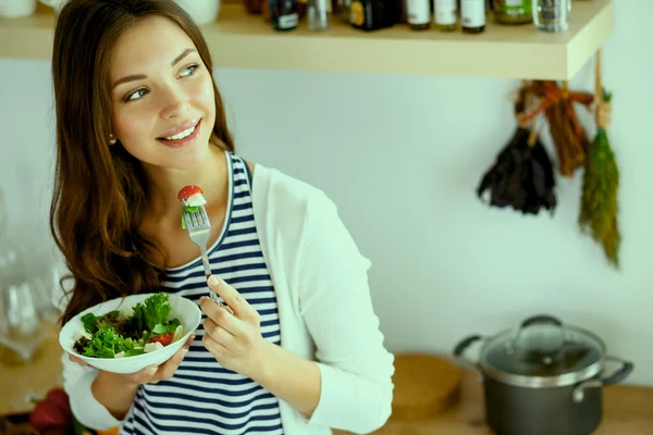 Young woman eating salad and holding a mixed salad