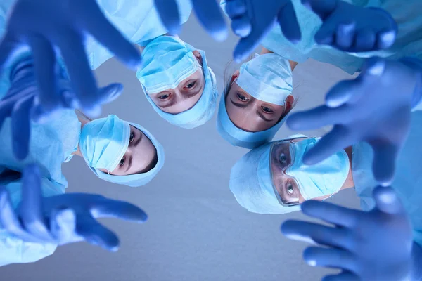 Surgeons team, wearing protective uniforms,caps and masks