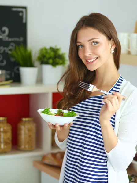 Young woman eating salad and holding a mixed salad