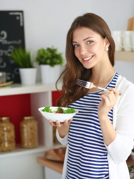 Young woman eating salad and holding a mixed salad