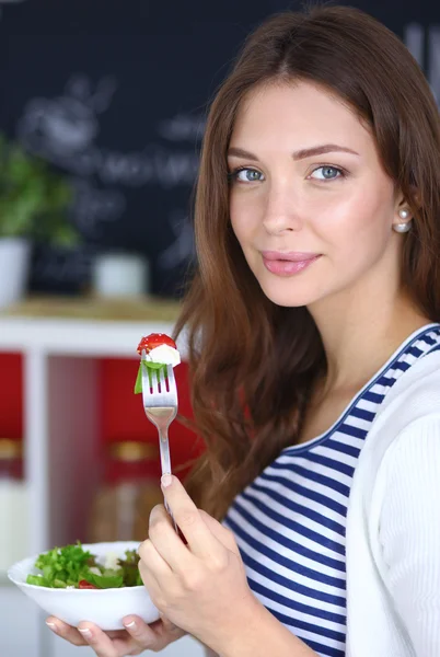 Young woman eating salad and holding a mixed salad