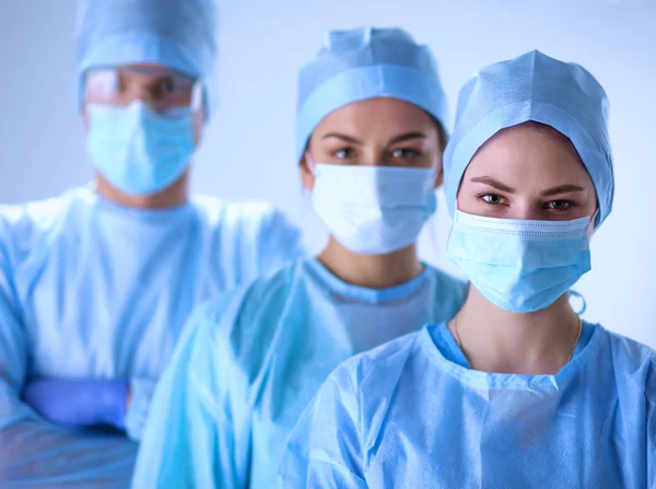 Surgeons team, wearing protective uniforms,caps and masks