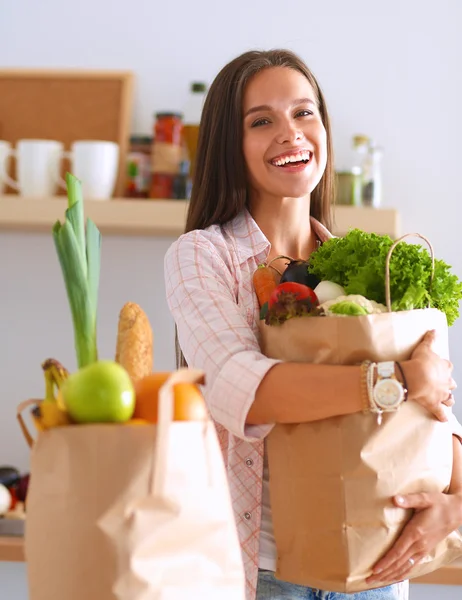 Young woman holding grocery shopping bag with vegetables