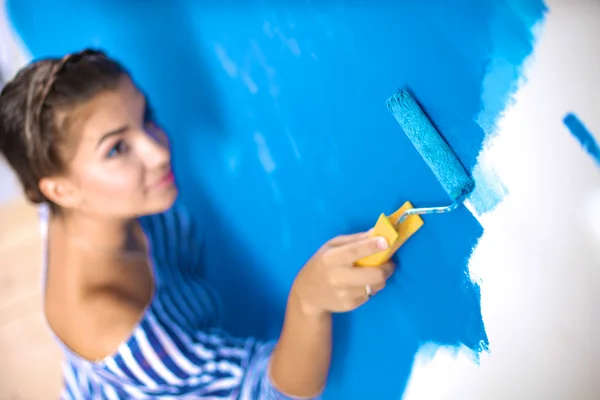 Happy beautiful young woman doing wall painting