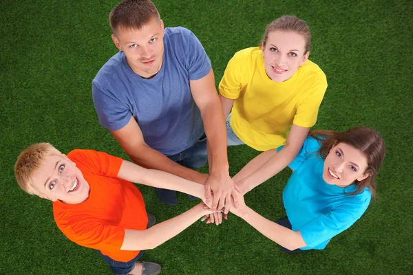 People joining their hands  on green grass