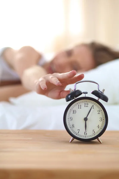 Young sleeping woman and alarm clock in bedroom at home