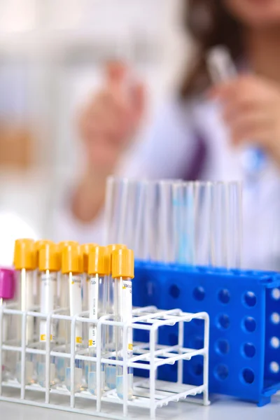 Woman researcher is surrounded by medical vials and flasks, isolated on white background