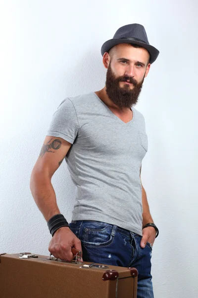 Portrait of handsome bearded man in hat standing with bad, isolated on white background