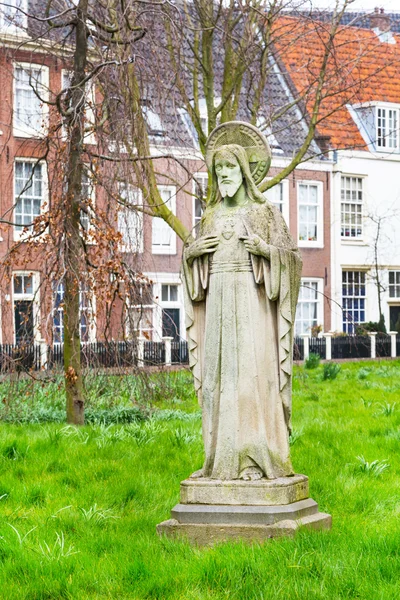 Begijnhof courtyard with Jesus statue and historic houses in Amsterdam, Netherlands