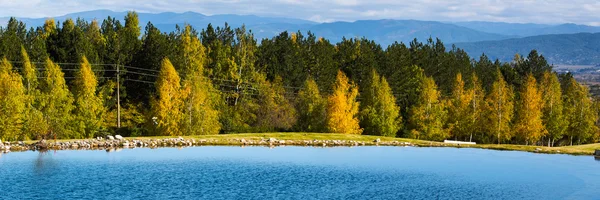 Beautiful blue Lake, green and yellow trees, mountains view background