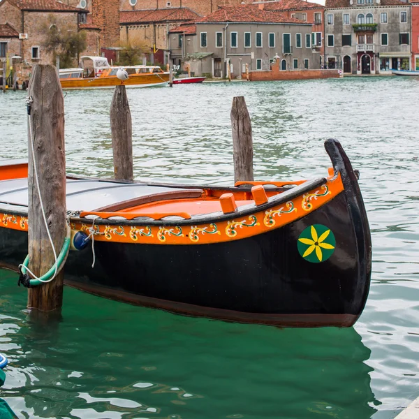 Colorful venetian gondola boat parked in the water, houses and canal view