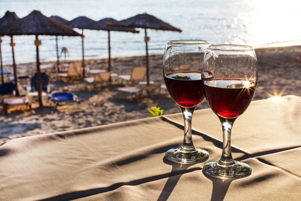 Two glasses of red wine with sun reflection, sea, summer vacation background